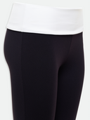 Black leggings worn with a white top on a light gray background