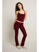 Woman wearing a burgundy tank top and pants on a plain background