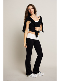 Woman wearing a black crop top, white tank top, and black pants on a plain background