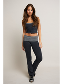 Woman wearing a two-tone tank top and pants on a plain background