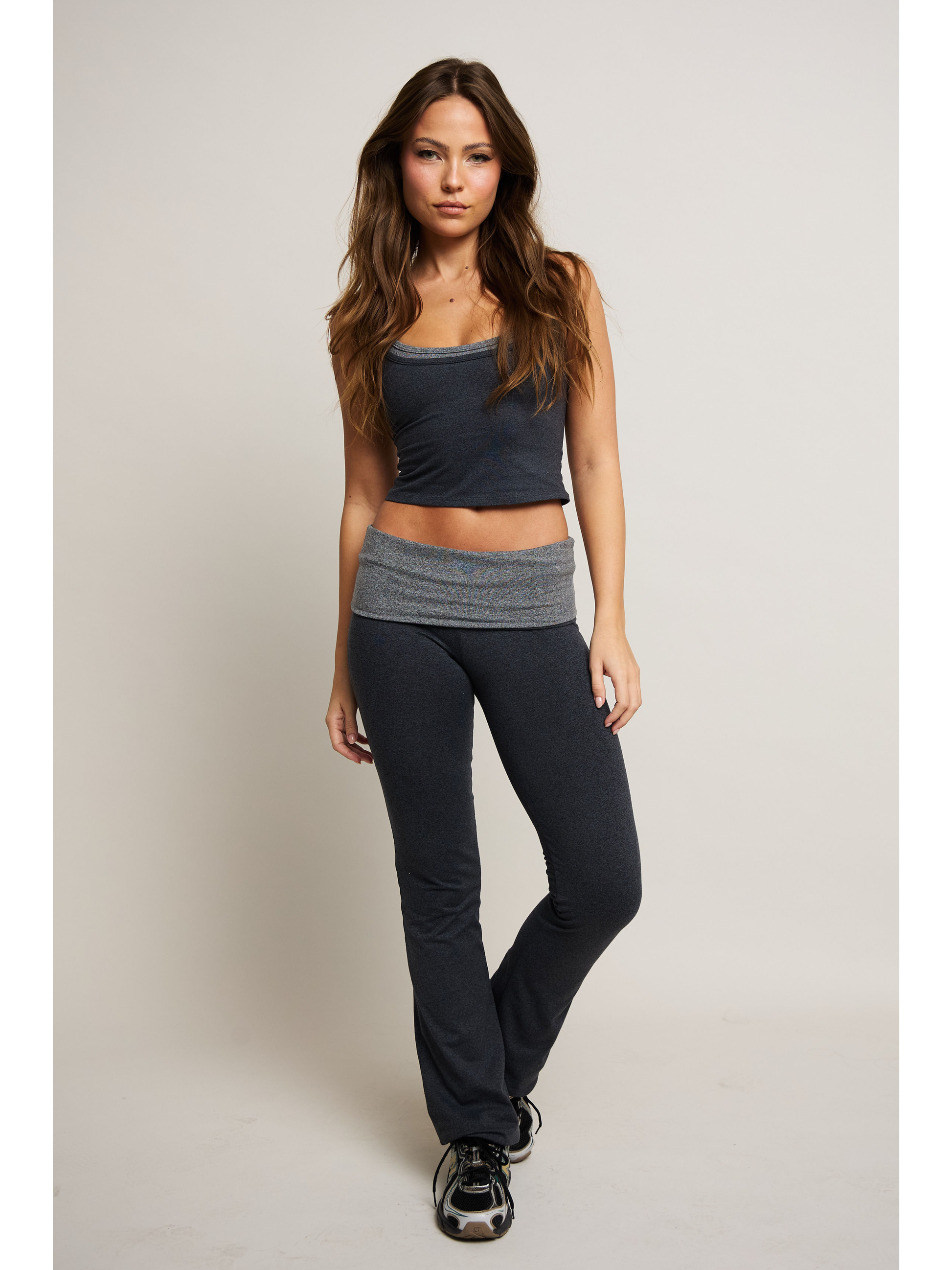Woman wearing a two-tone tank top and pants on a plain background