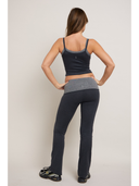 Woman wearing a tank top and gray leggings on a plain background