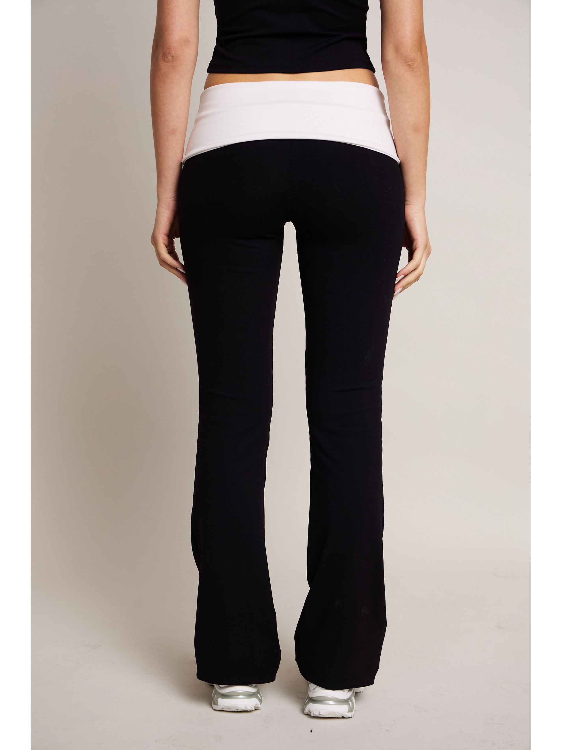 woman wearing black pants and a black top on a plain background