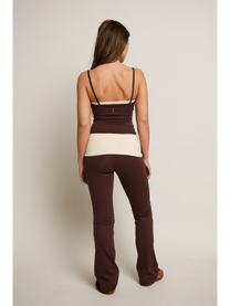 Woman wearing a two-tone top and brown pants on a plain background