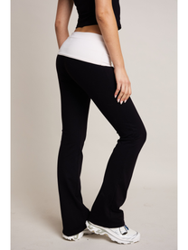 Person wearing black pants and a white top against a plain background