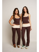 Two women wearing matching brown and beige outfits on a plain background
